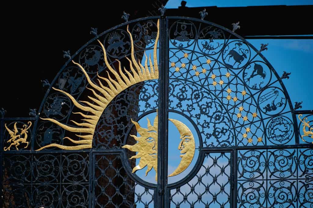 Beautiful forged gates with signs of the zodiac, the moon and the sun. Black metal gates.