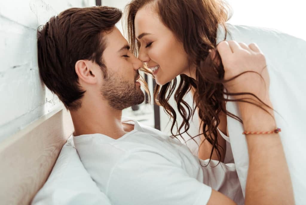 Happy young woman with closed eyes near cheerful boyfriend