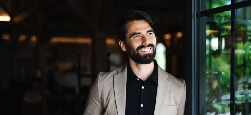 Handsome man smiling while staring outside the window.