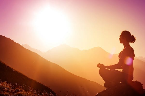 woman meditating on top of mountain