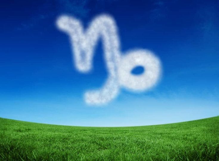 Cloud in shape of capricorn star sign against green field under blue sky