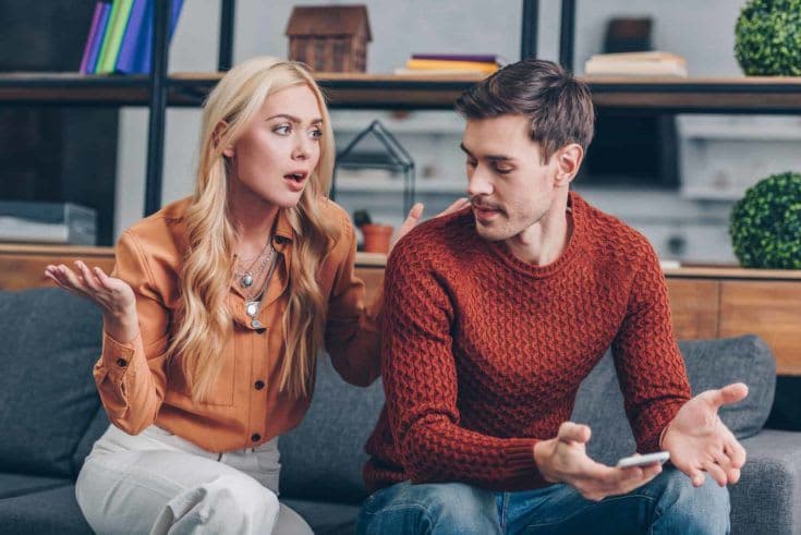 Emotional upset couple sitting on couch