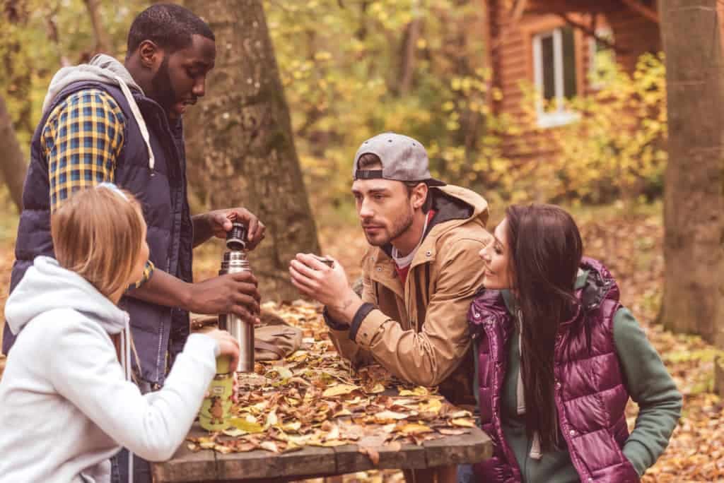 Friends pouring hot drink in forest