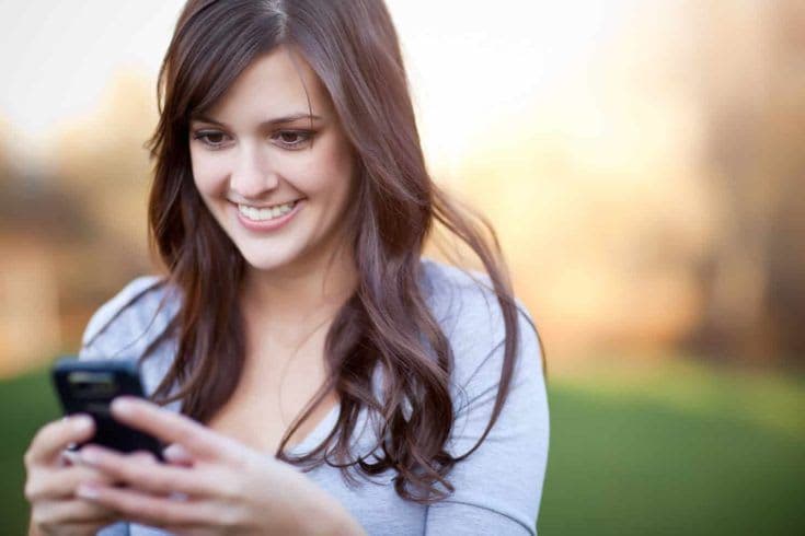 A portrait of a smiling beautiful woman texting with her phone