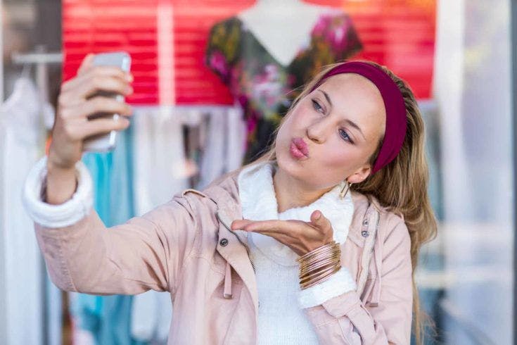 Woman blowing kiss and taking selfies at shopping mall
