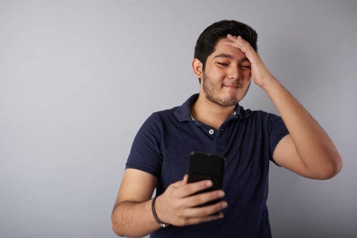 Man with pain look into smartphone screen isolated on gray background