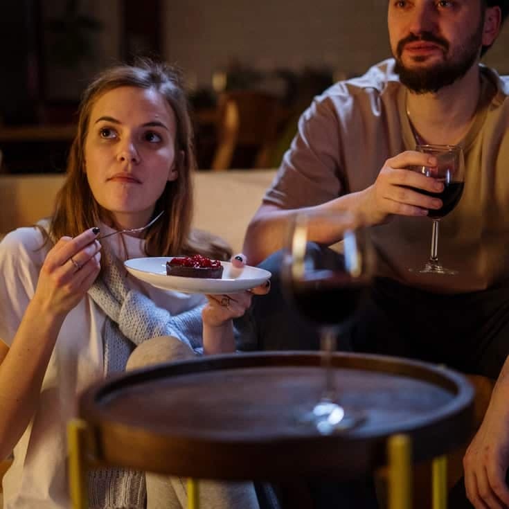 Woman eating cake and man holding a glass of wine