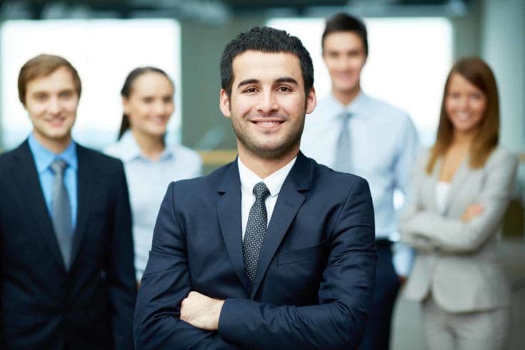 Group of friendly businesspeople with male leader in front