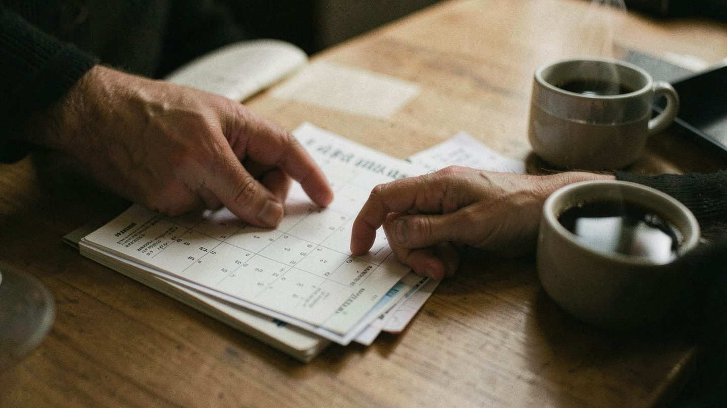 Hands with a calendar and receipts on a table