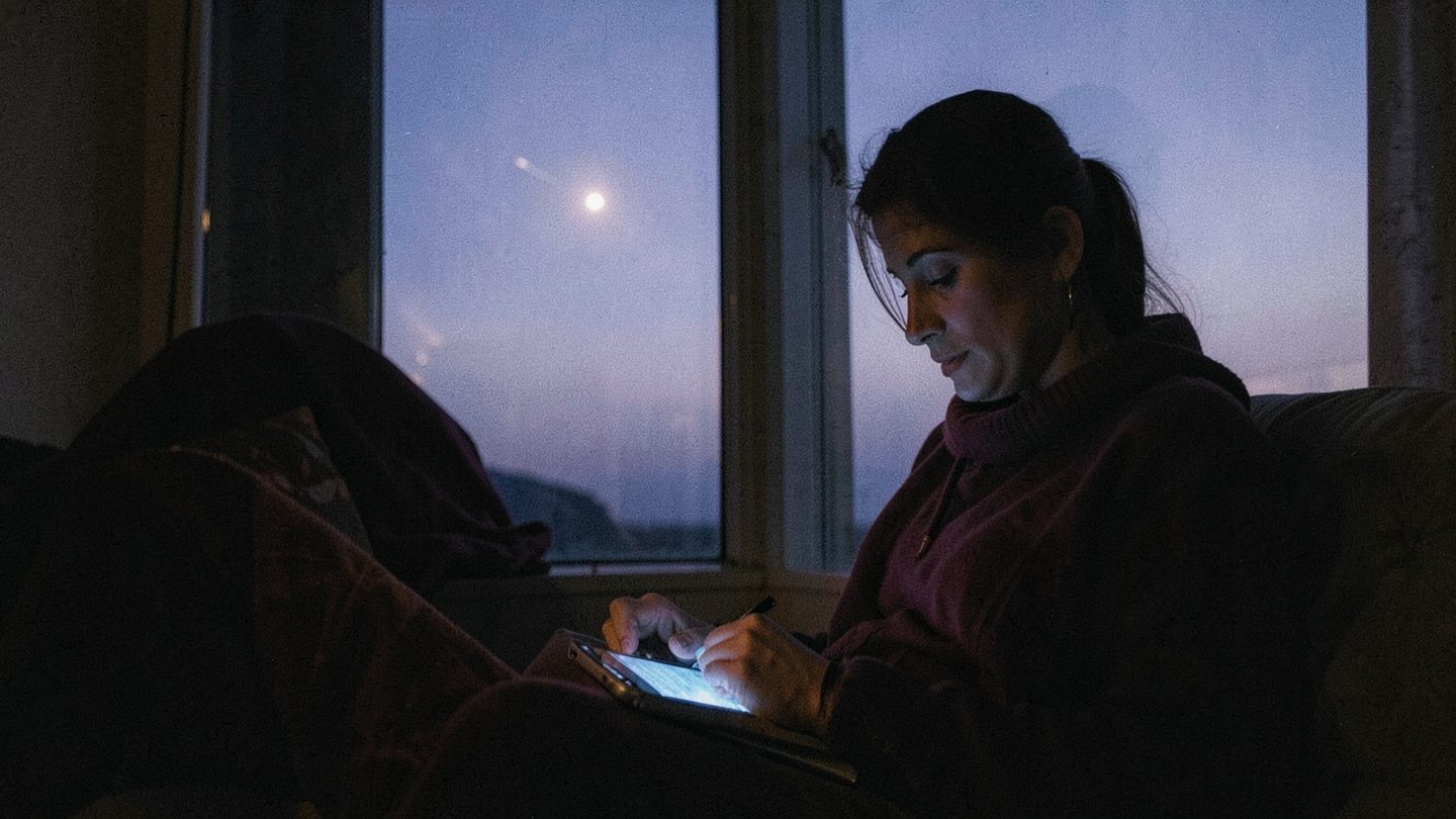 A person at dusk reviewing notes while looking out at the evening sky.