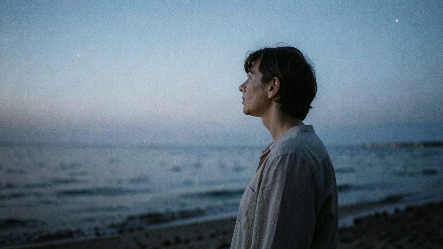 Editorial photograph of a contemplative person by the water at night